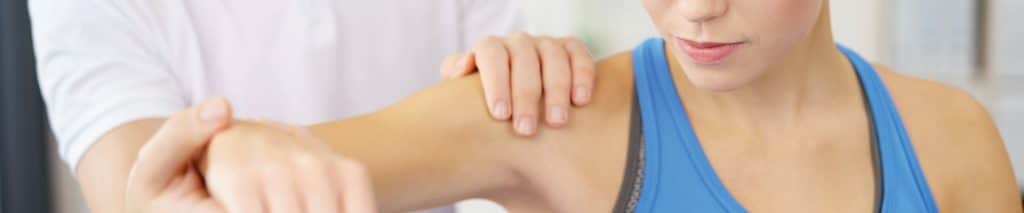 Ein Mann untersucht die Beweglichkeit des Armes einer Frau